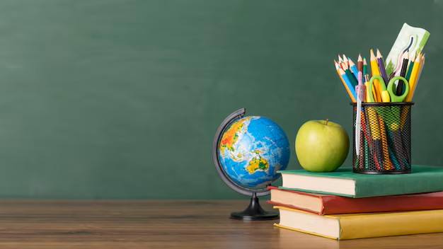 Globo terráqueo, manzana verde, lápices de colores y libros sobre una mesa, con un fondo de pizarra verde.